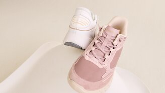 Zwei Frauen stehen nebeneinander, sie tragen schwarze Oberteile und umarmen sich freundlich vor hellem Hintergrund. | © Gabor Shoes GmbH, Rosenheim