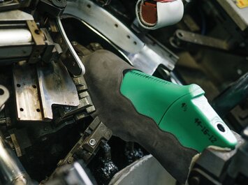 Grüne Schuhleiste mit aufgezogenem Lederteil in einer Maschine zur Schuhherstellung.