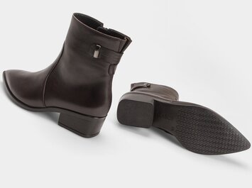 Dunkelrote Stiefelette mit seitlicher Schnalle neben ihrer profilierten Laufsohle auf hellem Hintergrund. | © Gabor Shoes GmbH, Rosenheim