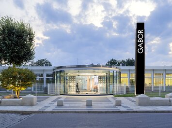 Modernes Firmengebäude mit Glasfassade und großem Gabor-Schriftzug am Eingang. | © Gabor Shoes GmbH, Rosenheim