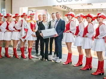Eine Gruppe von Menschen mit Karnevalstänzerinnen in roten Kostümen und Gabor-Geschenkboxen. | © Gabor Shoes GmbH, Rosenheim