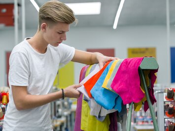 Person begutachtet bunte Lederstücke in einer Produktion. | © Gabor Shoes GmbH, Rosenheim