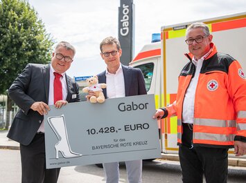Drei Personen übergeben einen großen Spendenscheck von Gabor an das Bayerische Rote Kreuz. | © Gabor Shoes GmbH, Rosenheim