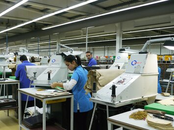 Mitarbeitende arbeiten an Maschinen in einer Produktionshalle. | © Gabor Shoes GmbH, Rosenheim